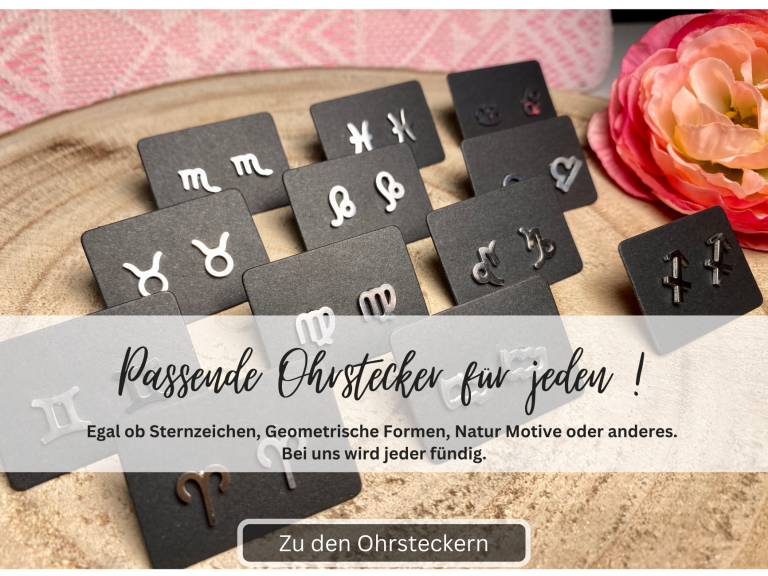 Schmuckstücke mit verschiedenen Zeichen auf schwarzen Karten, dekoriert mit einer Blume.
